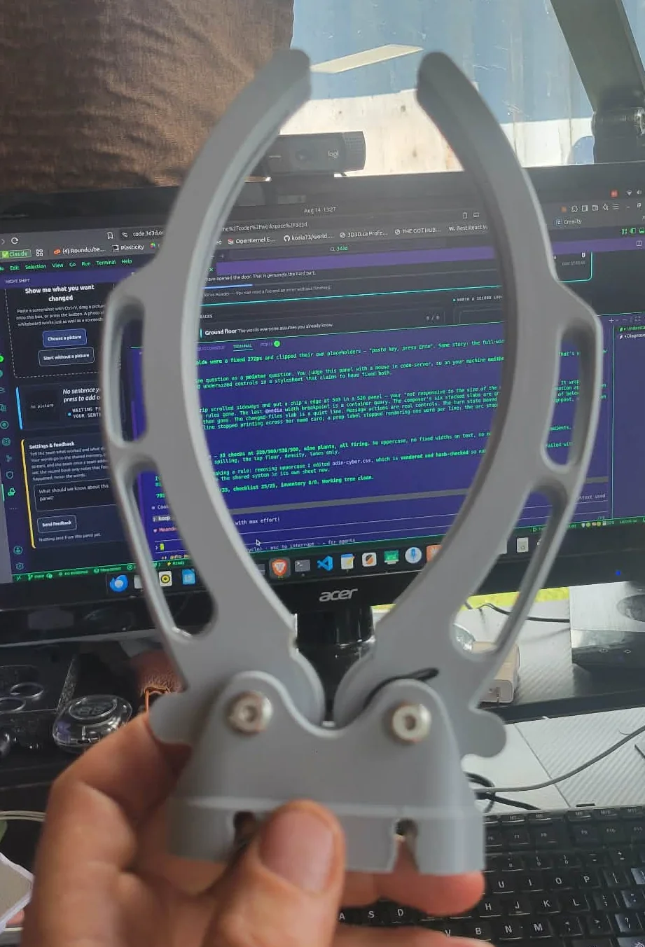 The finished plate clip assembled, both sprung arms on the base, held in a hand
