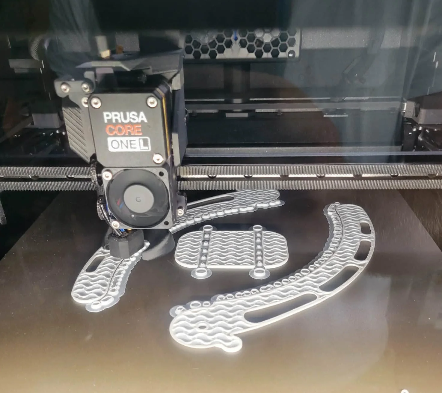 Both arms and the base printing on the bed of a Prusa Core ONE L