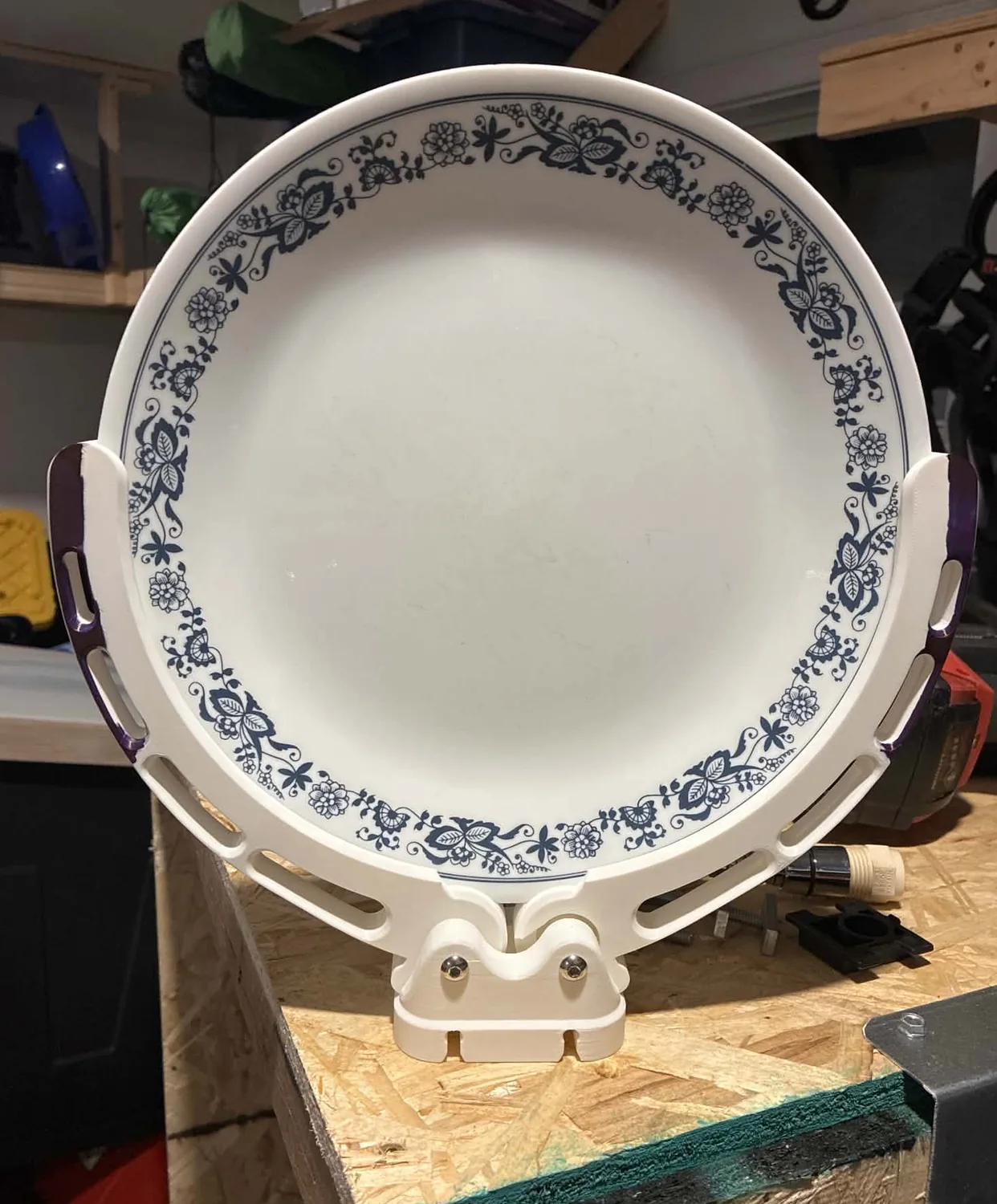 The finished clip holding a ten inch patterned plate upright on a workbench